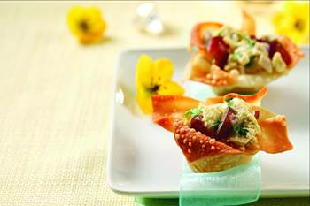 Curried chicken salad in wonton cups sitting on white plate with yellow flowers