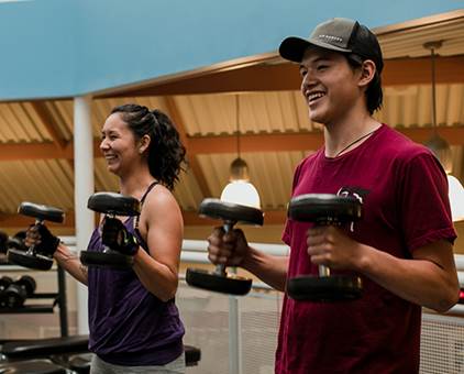 A woman and a teenage boy lifting weights at a gym