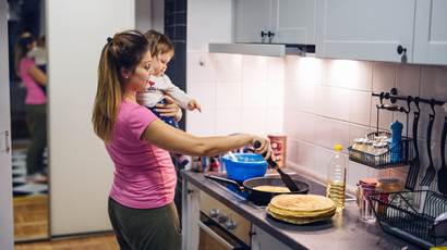 mother holding baby in kitchen cooking crepes