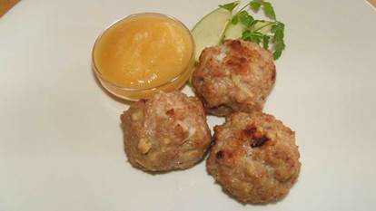 Three turkey and apple meatballs on a plate with applesauce