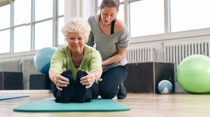 woman sitting on floor stretching legs with personal trainer