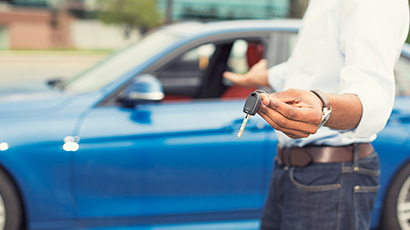 Man holding car keys in front of car