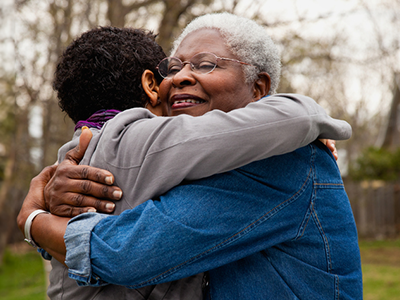 A black grandmother hugs her grandchild